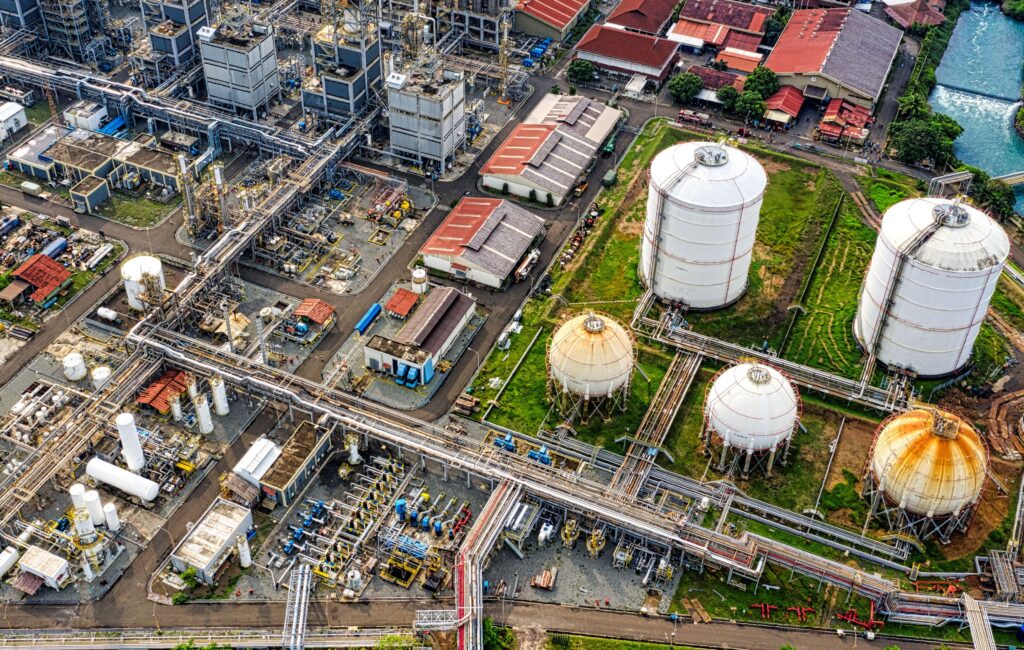 Aerial view of a large industrial complex with processing units, storage tanks and interconnected pipelines.